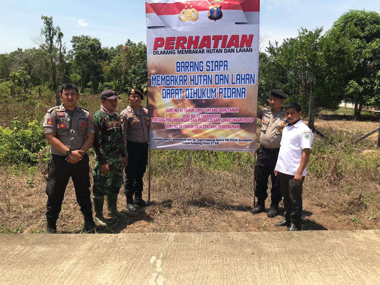 Anggota Polsek Muara Pahu bersama perwakilan Koramil dan Kecamatan memasang spanduk himbauan Karhutlah