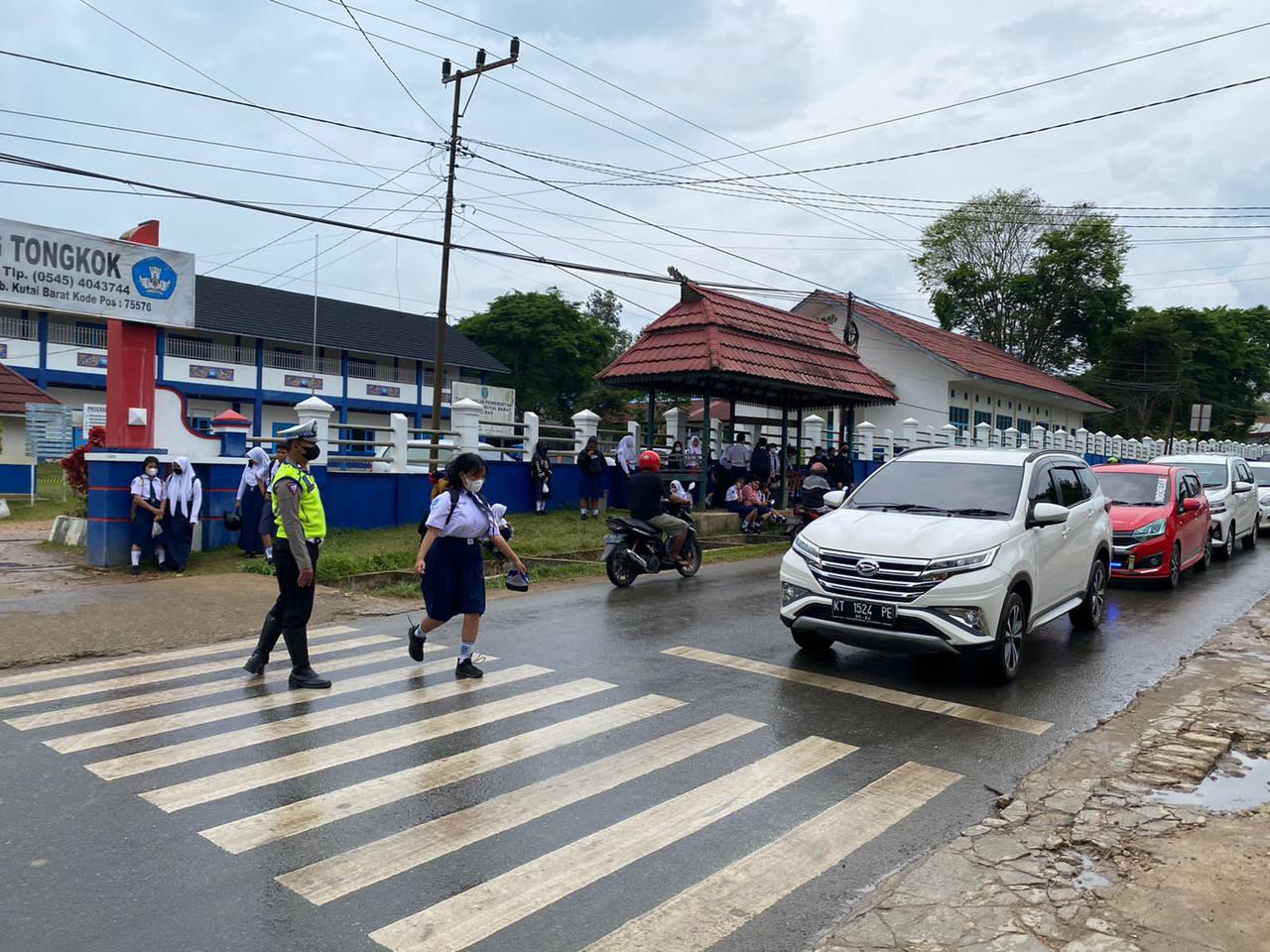 ATUR LALU LINTAS PAGI, SATLANTAS POLRES KUTAI BARAT BANTU ANAK SEKOLAH MENYEBRANG JALAN.